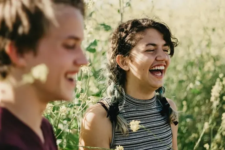 Two friends laughing in a field of flowers