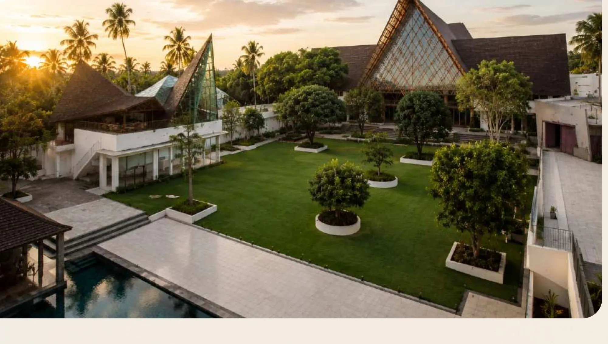 The property from above at sunset: roofs, lawn and pool